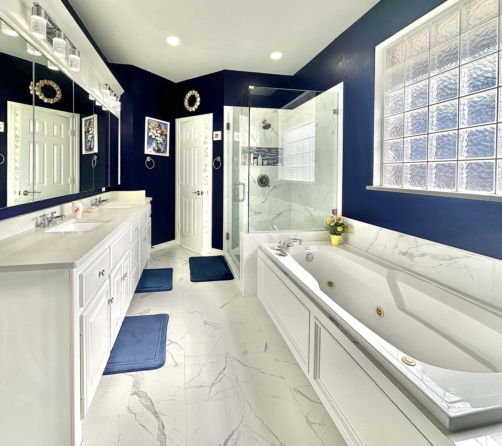 Ruime badkamer met ingebouwd bubbelbad en aparte glazen douche, dubbel wastafelmeubel en donkerblauwe wanden